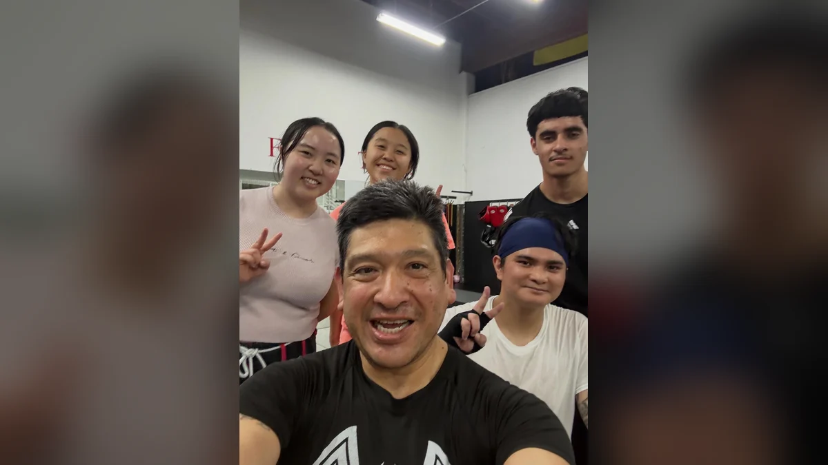 Smiling adult students and their coach taking a selfie after a martial arts class at AB MMA in San Francisco