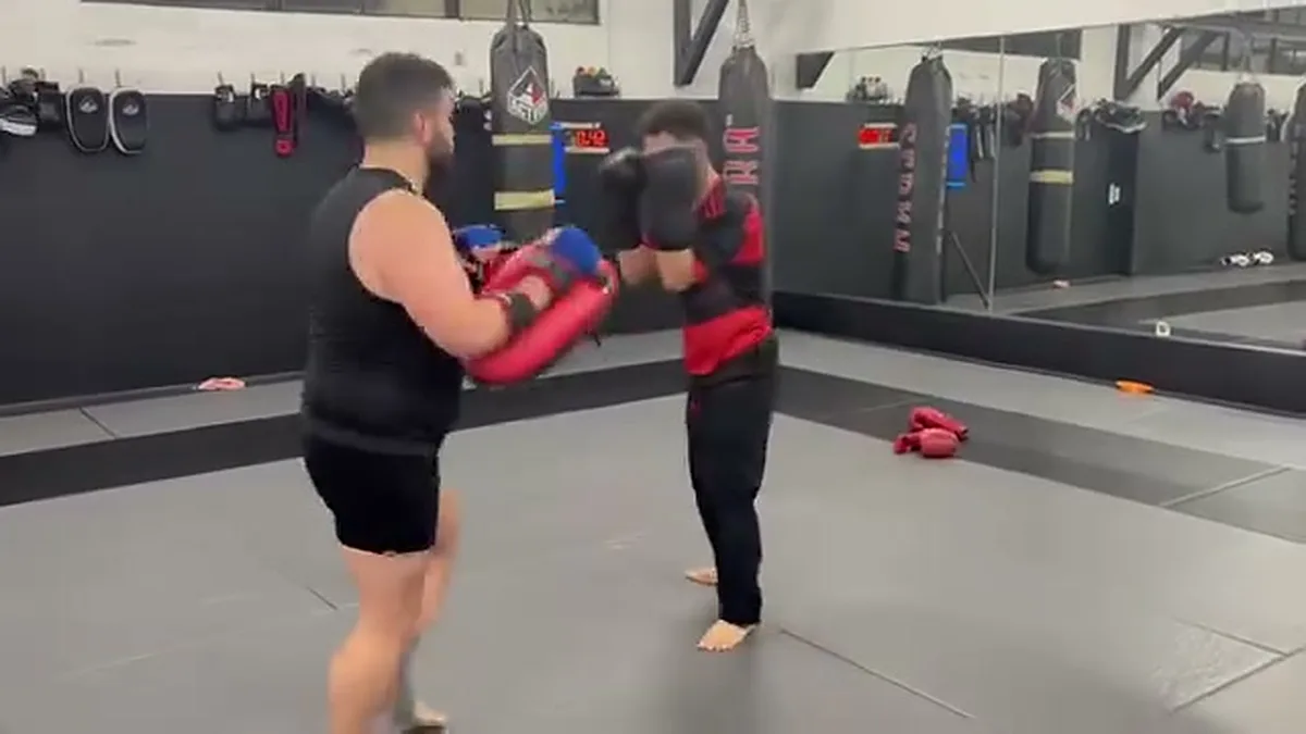 Coach holding Muay Thai pads for a student at AB MMA in San Francisco