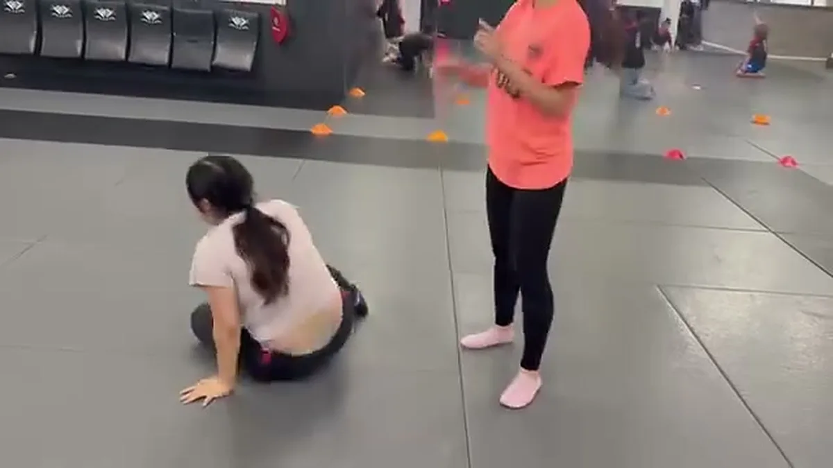 Student practicing a safe technical stand-up from the ground in a self-defense class in San Francisco