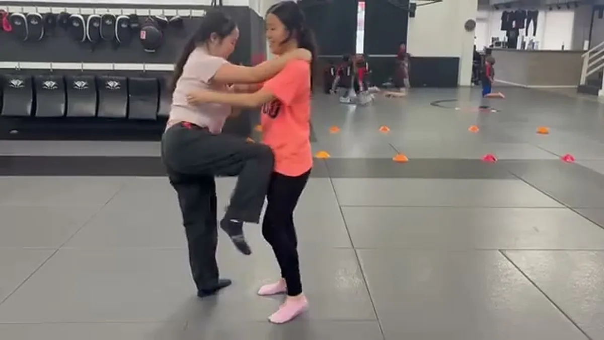 Two women practicing a knee strike from the clinch in a self-defense class at AB MMA in San Francisco