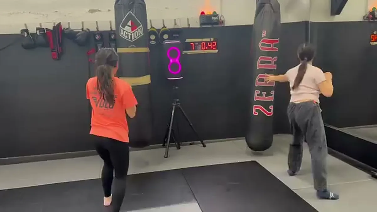 Two women hitting heavy bags during timed rounds in a Muay Thai class in San Francisco