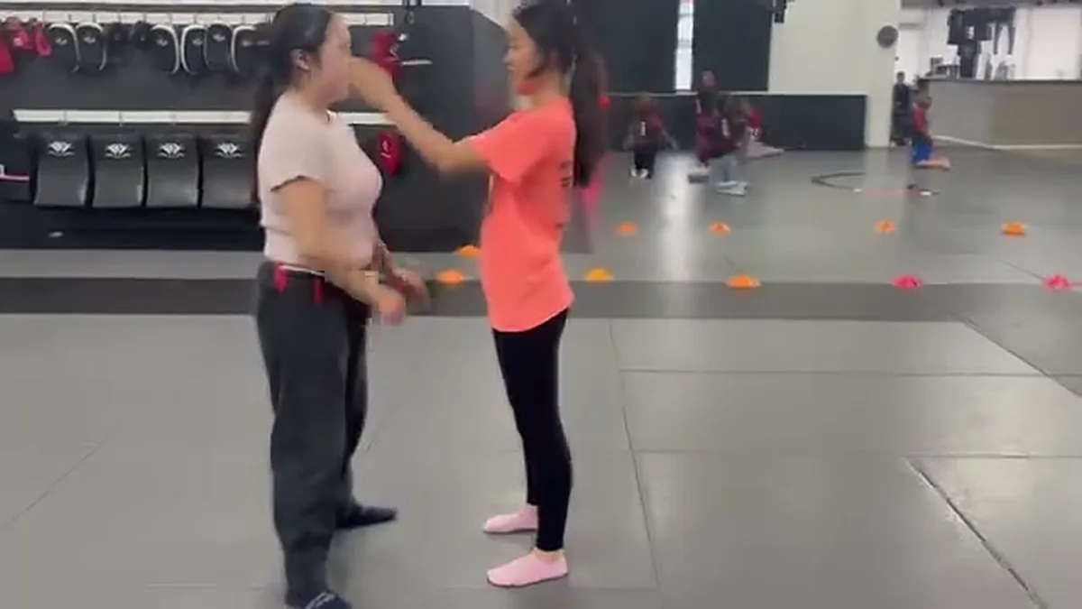 Woman using her hands to create distance from a training partner in a women's self-defense class in San Francisco