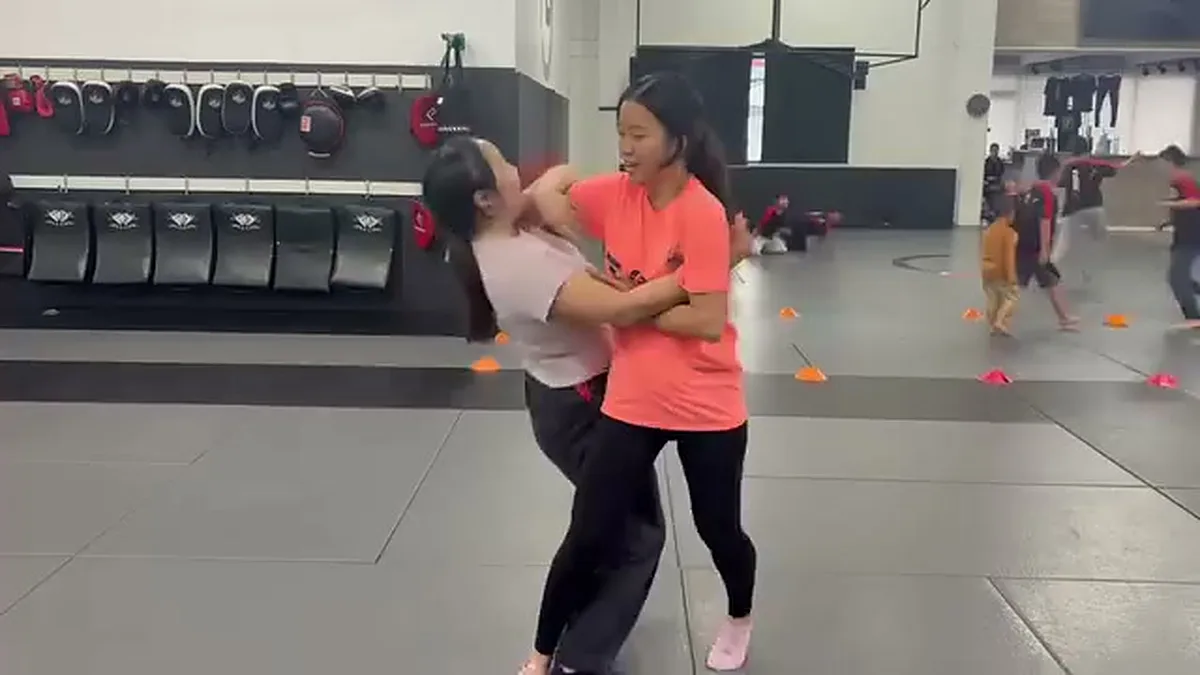 Woman practicing breaking a clinch during a self-defense drill at AB MMA in San Francisco